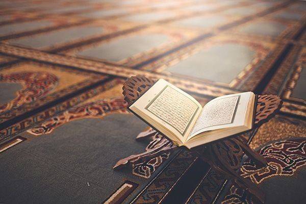 Eau coranisée : Coran ouvert sur un lutrin, récitation de versets pour la coranisation en Islam