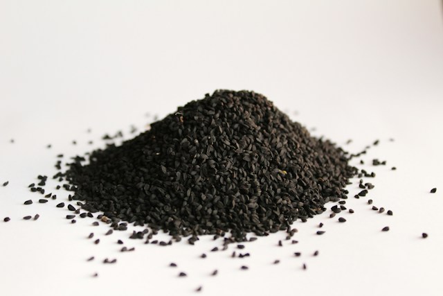 Graines noires de nigelle (Nigella sativa) sur fond blanc